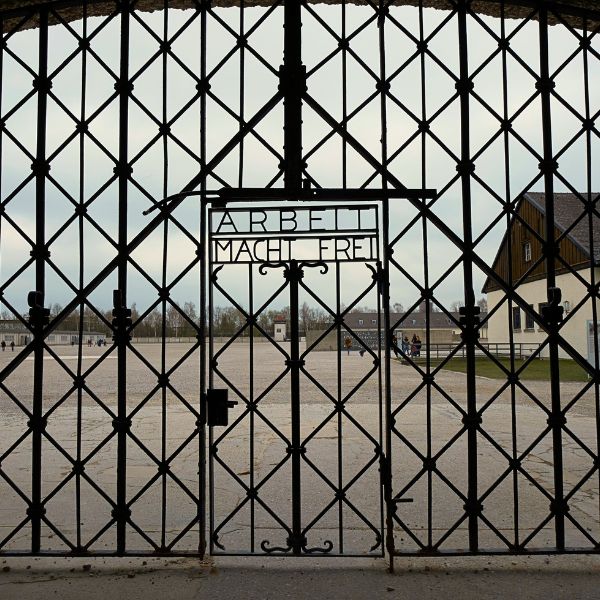 Iron rod gates with the words, "work makes you free" written in German and a light grey building behind it