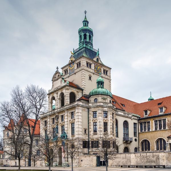 Munich Bavarian National Museum grey building with red tile roof and green domed towers set against a cloudy day