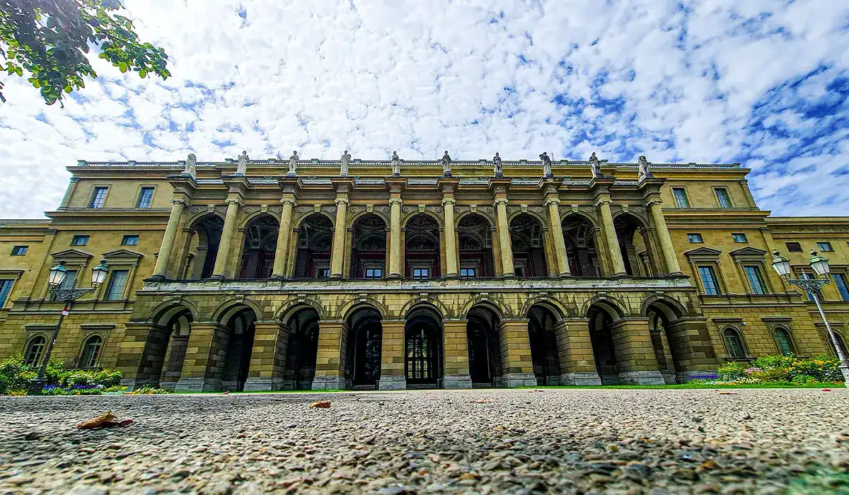 Wide-angle view of the Munich Residenz with tall arched windows under a partly cloudy sky.