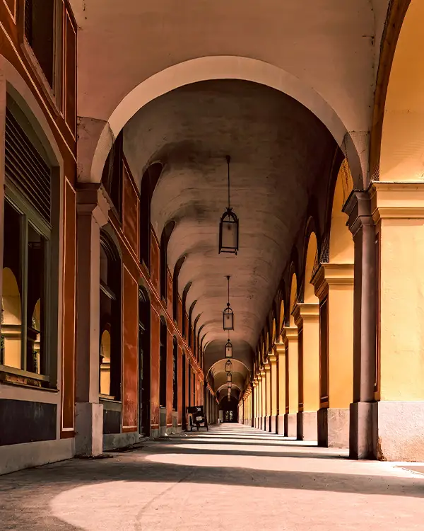 Long corridor with repeated archways and hanging lanterns in the Munich Residenz gardens