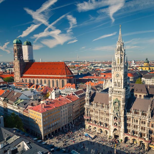 Munich skyline with Gothic style New Town Hall and the red roof Frauenkirche surrounded by buildings and blue sky