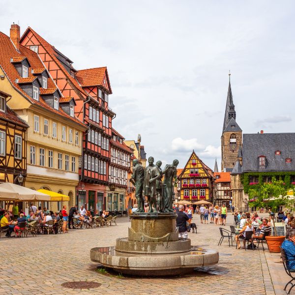 Fountain in Quedlinburg Square, Germany people around a water fountain in square with half-timbered houses and church in  Quedlinburg Square, Germany