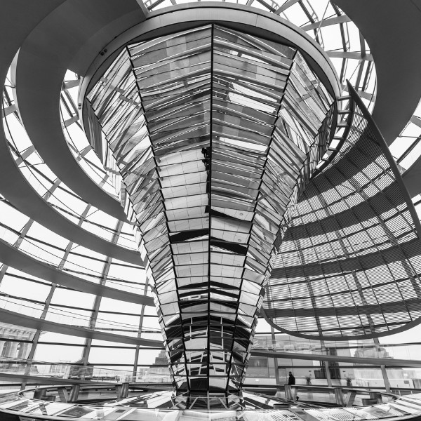 Inside the Reichstag dome Black and white photo of a large, futuristic glass and steel spiral structure inside a spacious building, with a person standing near the railing on the lower level.