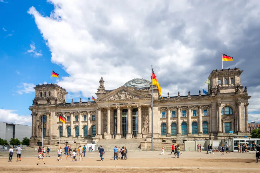 Reichstag building in Berlin with German flags and the glass dome visible above the pediment