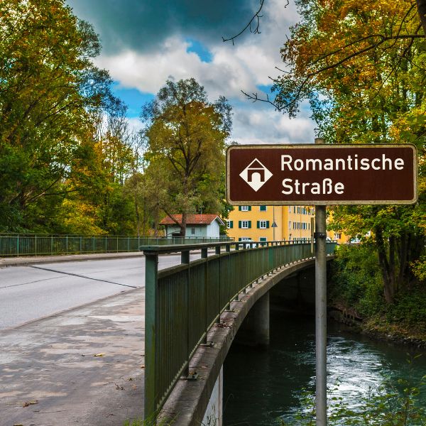 Road sign by bridge and river displaying the Romantic Road near Rothenburg