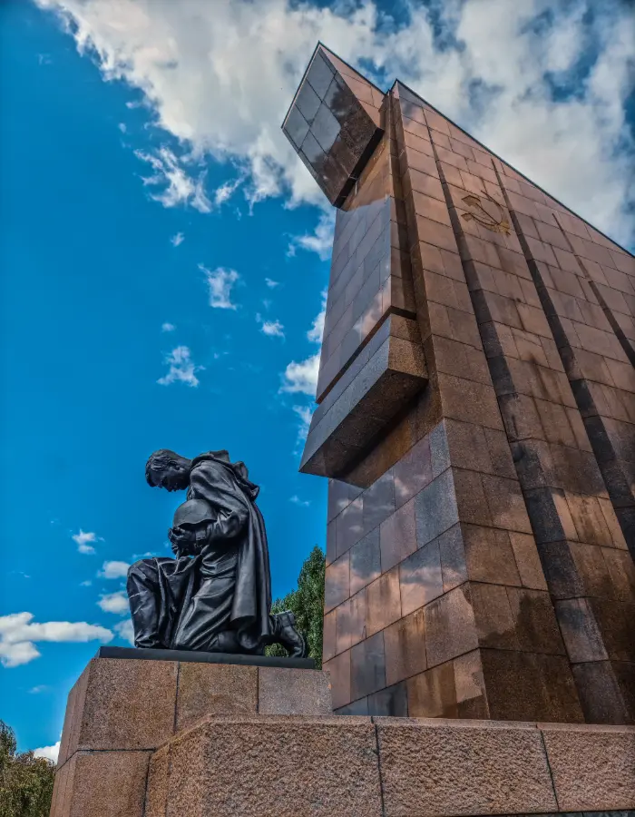 Kneeling bronze soldier and red granite flag at the Soviet War Memorial in Treptower Park, Berlin