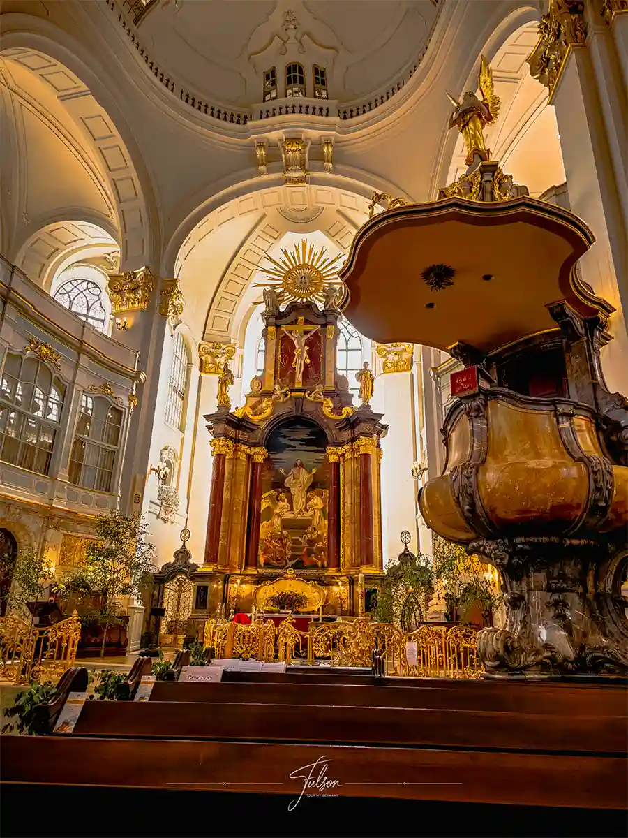 Ornate baroque church interior with high vaulted ceilings, golden altar, elaborate woodwork, and decorative statues, viewed from the pews. Ornate baroque church interior with high vaulted ceilings, golden altar, elaborate woodwork, and decorative statues, viewed from the pews.