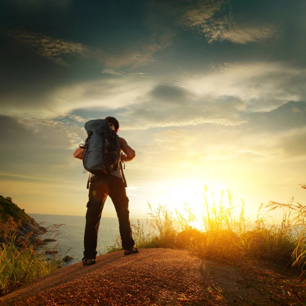 Traveler ready for new adventures. Hiker standing a sand dune at sunrise under a dark sky.