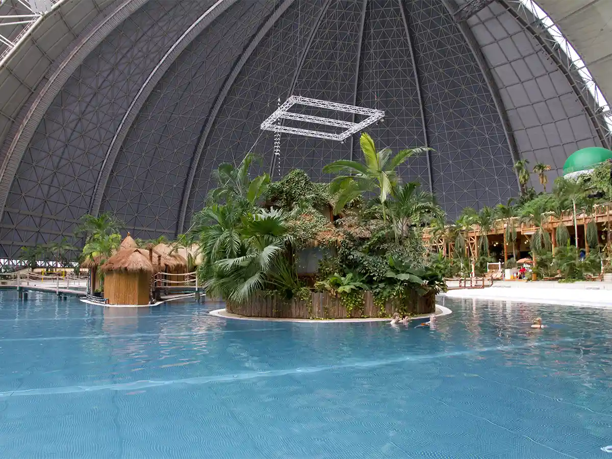 Lagoon pool and thatched cabanas under giant dome at Tropical Islands Resort—fun indoor oasis to visit in Brandenburg.