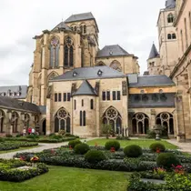 A historic European cathedral framed by manicured gardens and blooming flowers, representing one of Germany's UNESCO sites.