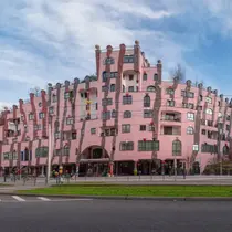 The Green Citadel of Magdeburg, a surreal pink building with irregular windows and whimsical towers designed by Friedensreich Hundertwasser.