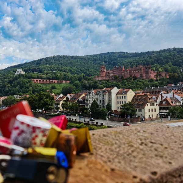 View of the red sandstone Heidelberg Castle with houses and love locks in front
