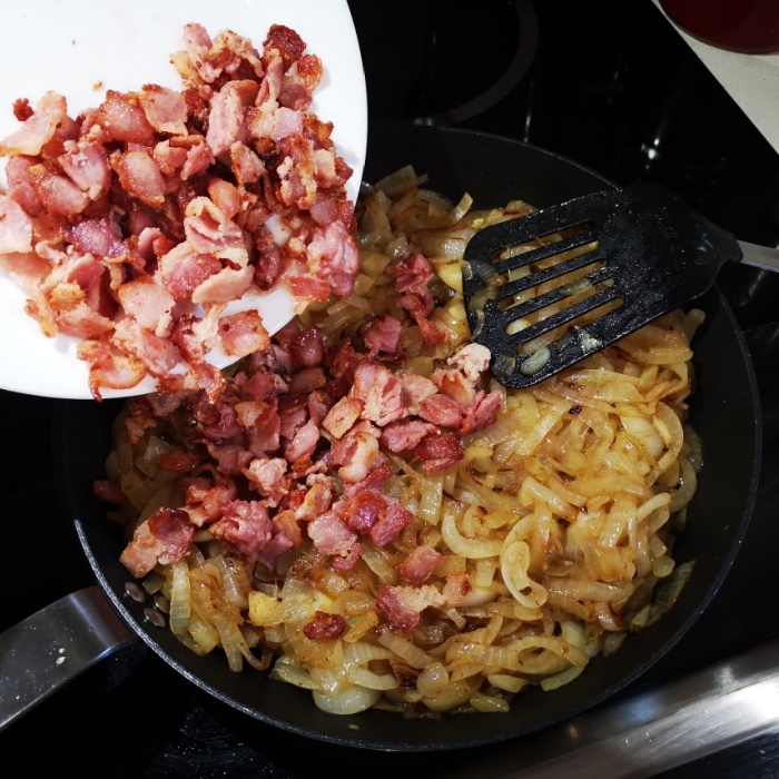 adding fried bacon to caramelized onions