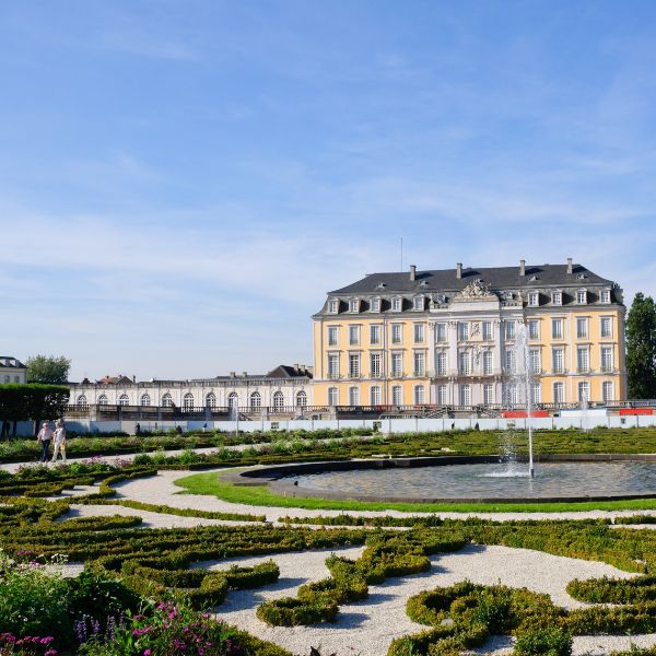 Castles of Augustusburg in Germany: white three-storey building behind landscaped grounds with fountain
