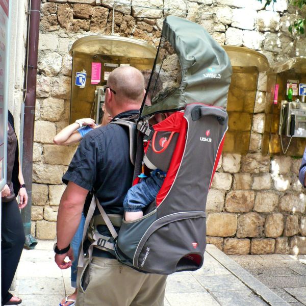 Father with a baby backpack carrier in front of stone wall