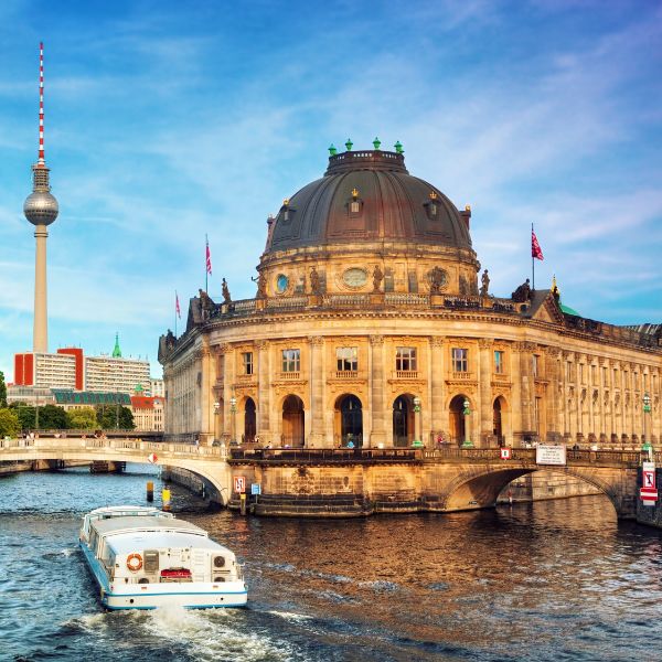 Bode Museum in Berlin, grey domed building along the water with a boat going past.