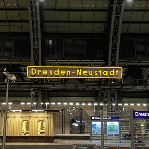 Train station with a neon sign displaying 'Dresden Neustadt'