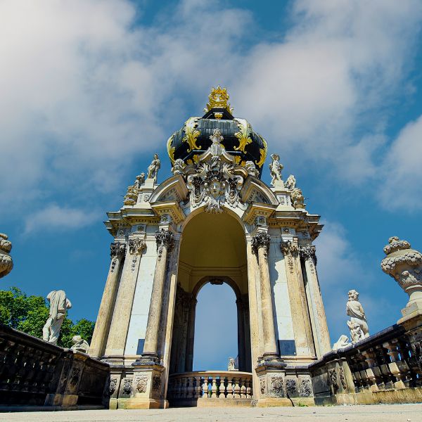 An ornate palace gate topped with a black and gold crown at Zwinger Palace
